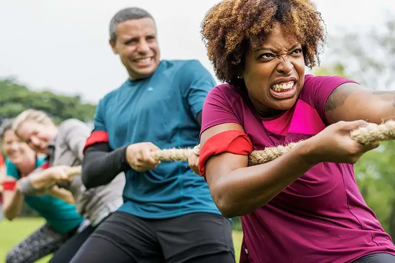 People playing tug-of-war with a rope at a park